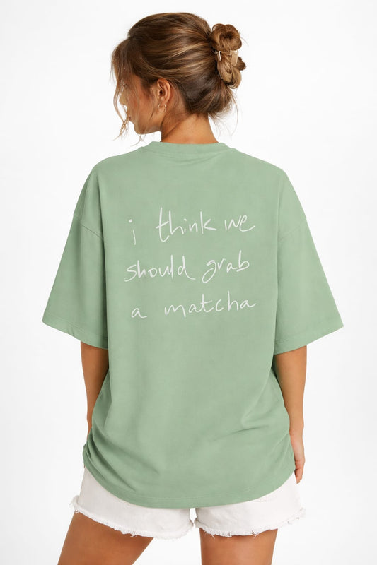 Person wearing a matcha t-shirt with text on the back, standing against a white background